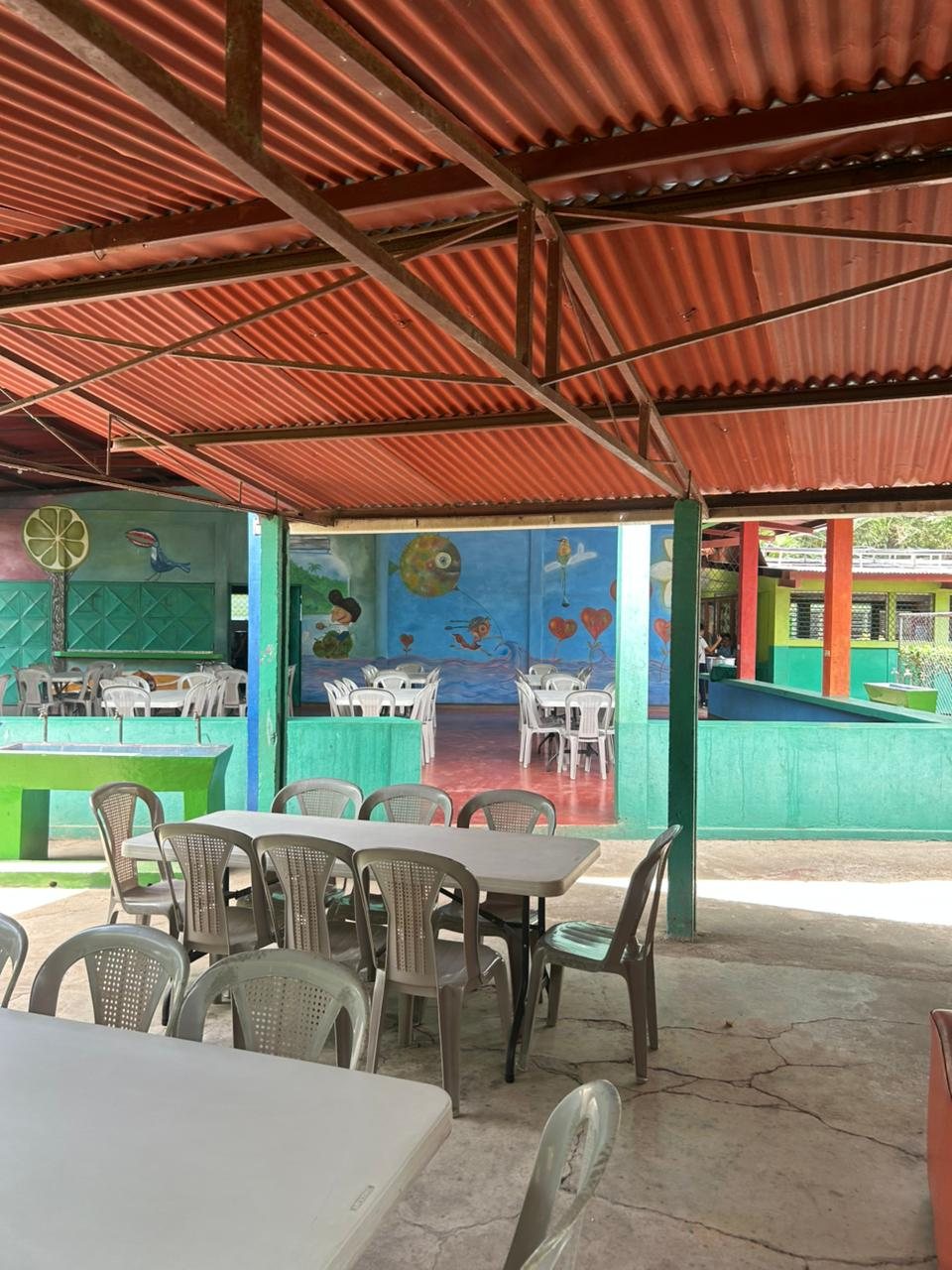 Comedor escolar con techo de zinc y murales pintados a mano